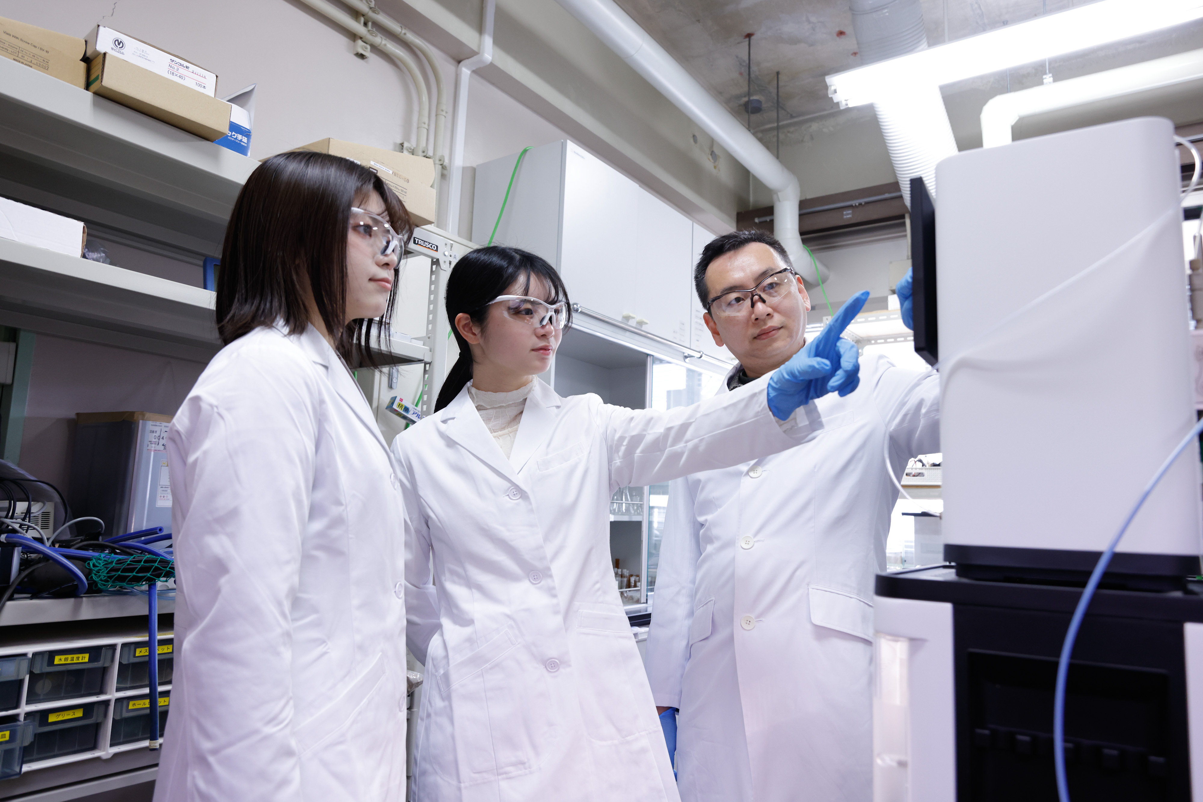 写真：女子学生3人が教員から実験の説明を受けている